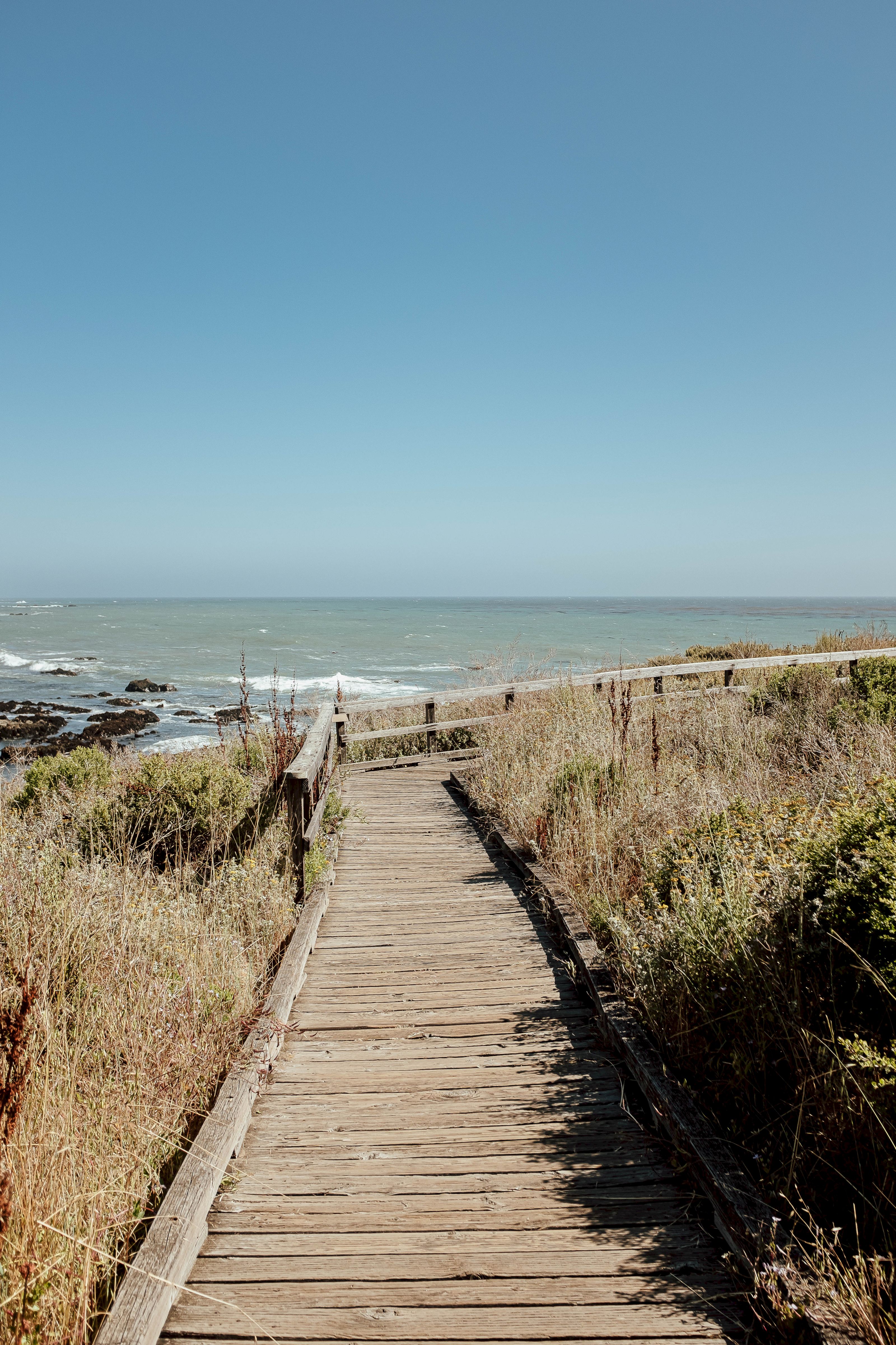 A wooden pathway leads to the beach with ocean views.