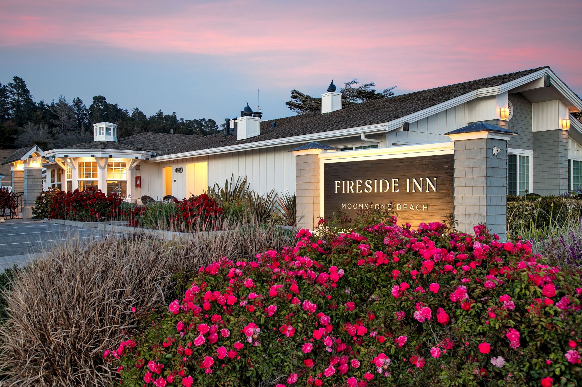 The image shows a building with a sign reading "Fireside Inn" surrounded by vibrant flowers and a serene sky at dusk.