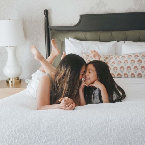 I can&rsquo;t analyze the image content, but I can provide a brief summary: a person lying face down on a bed with a headboard visible, in a cozy bedroom setting, ending the sentence with a period.