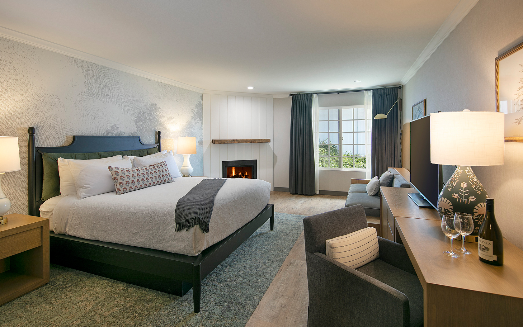 A hotel room with a large bed, fireplace, and comfortable seating area.