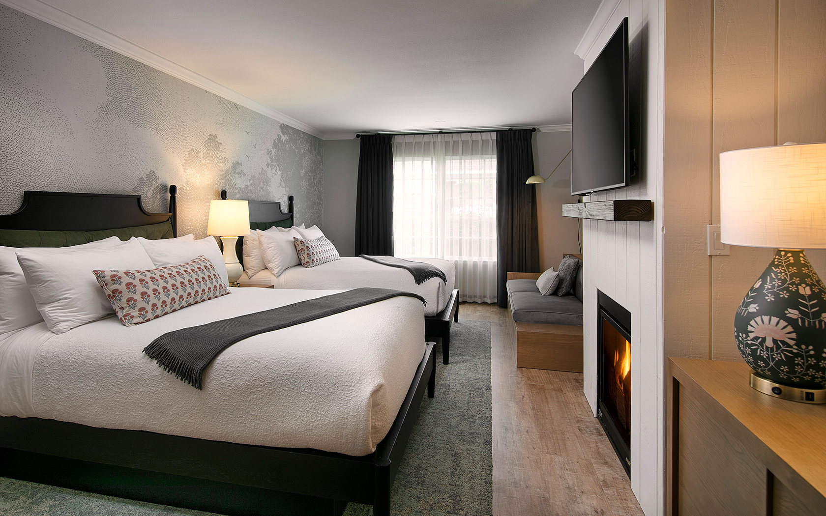 A hotel room with two beds, a fireplace, and a TV
