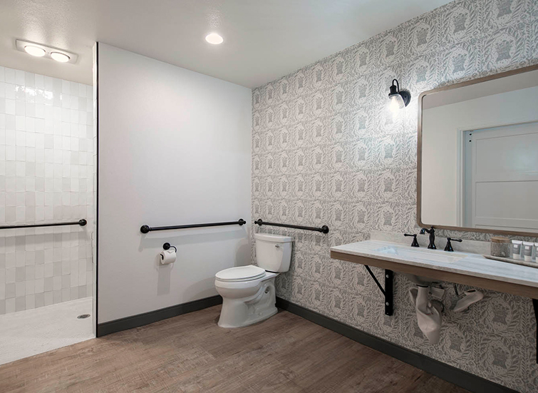 A clean bathroom with a toilet, shower, sink, and mirror.