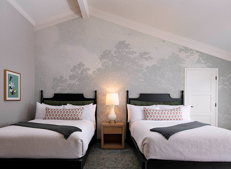 A room with two twin beds, a nightstand with a lamp, and a picture frame on the wall.