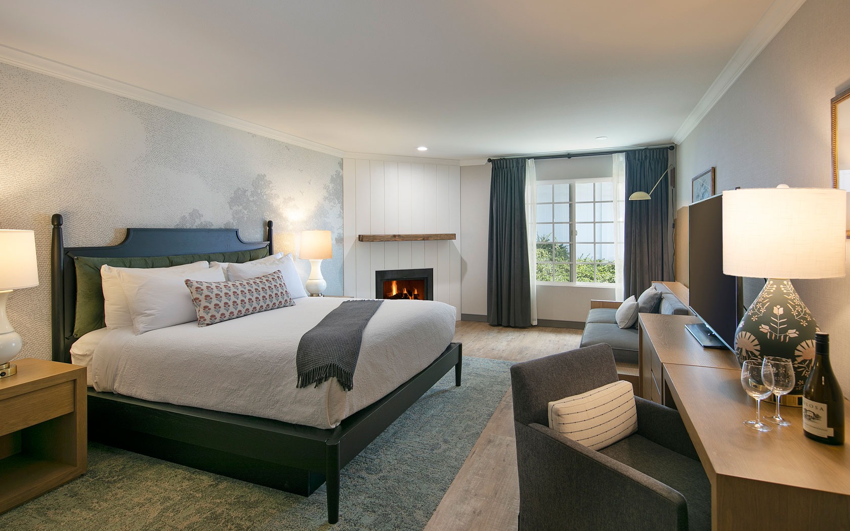 A hotel room with a large bed, fireplace, and seating area.